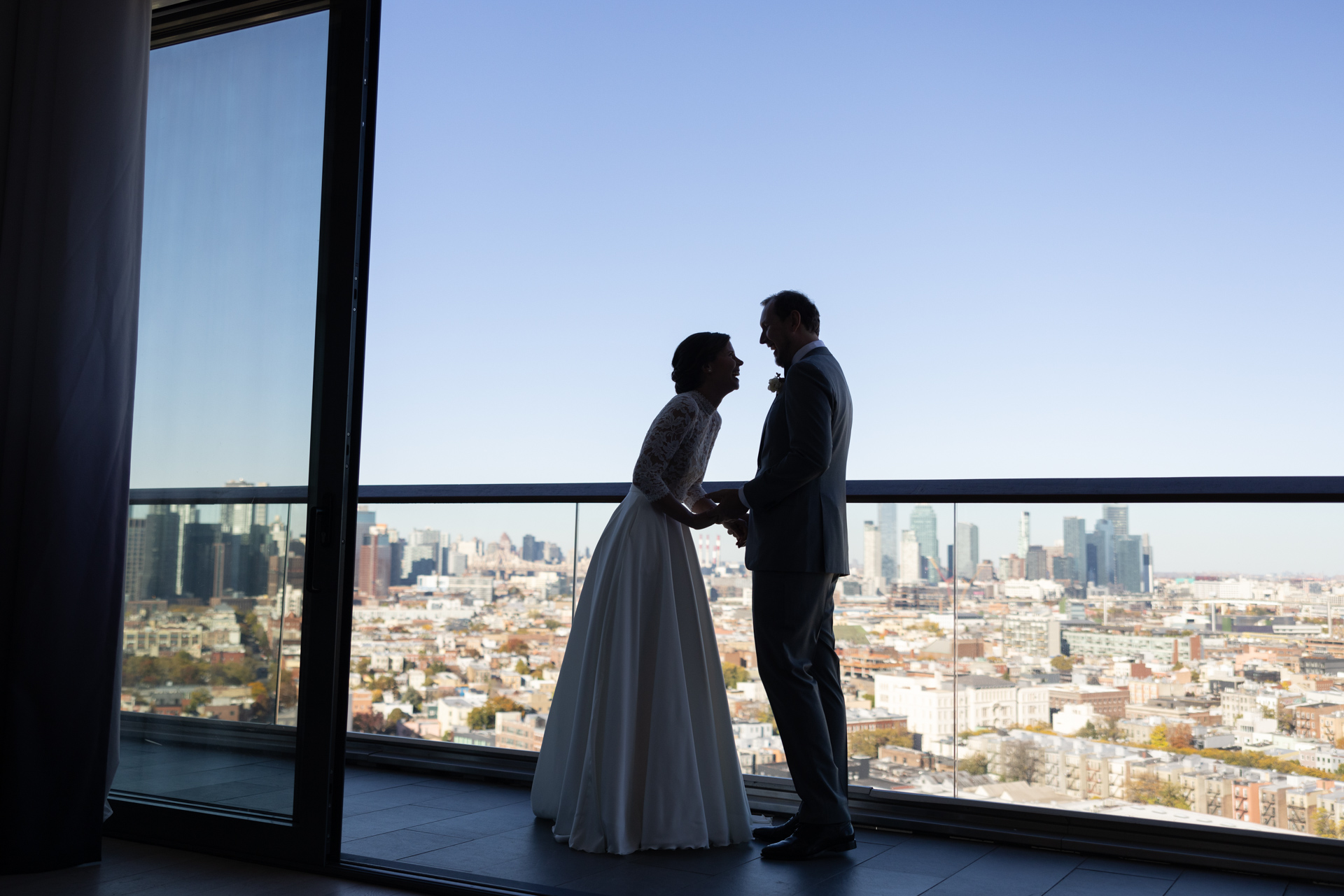 Bride and groom silhouetted against city skyline.