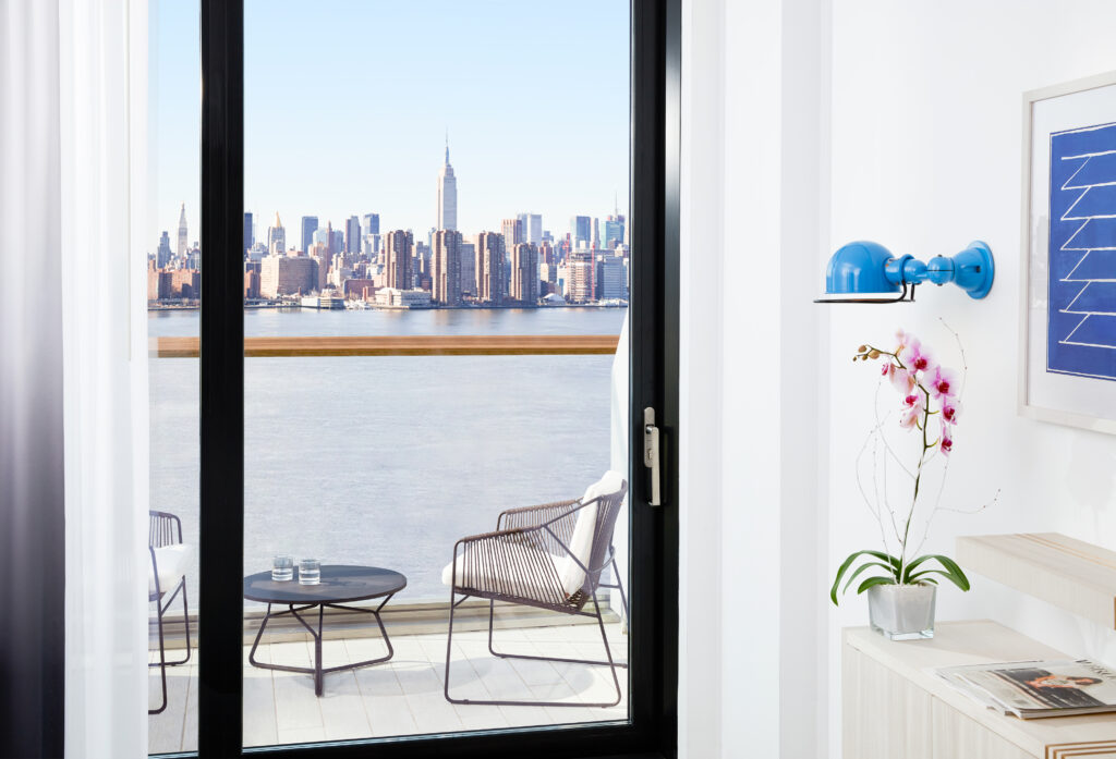 Balcony seating with Manhattan skyline and river view beyond.