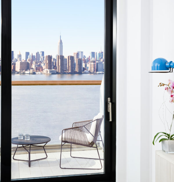 Balcony seating with Manhattan skyline and river view beyond.