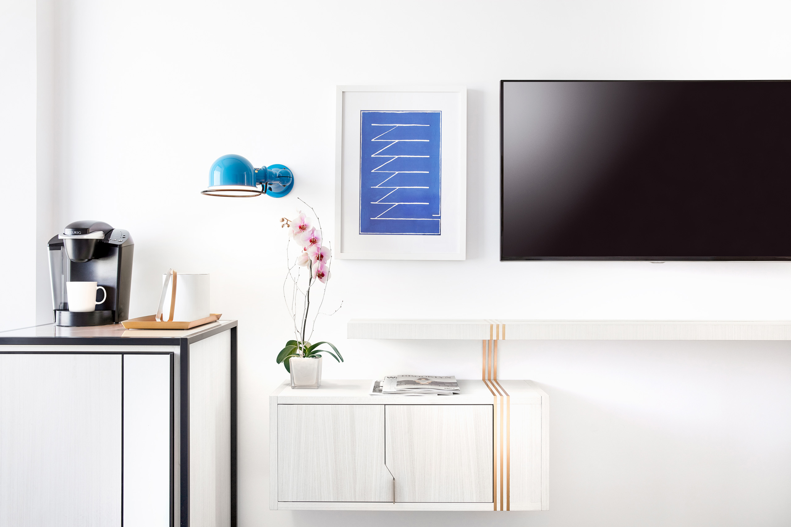 Coffee station, orchid, and TV in modern hotel room.