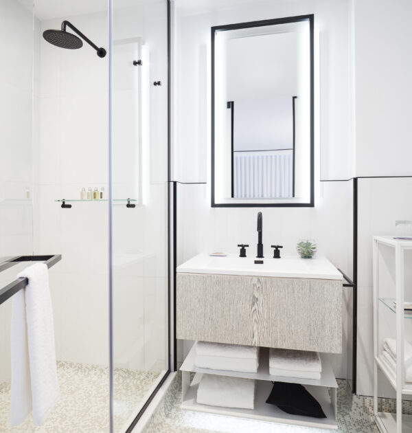 Sleek bathroom with walk-in shower, illuminated mirror, and black fixtures.