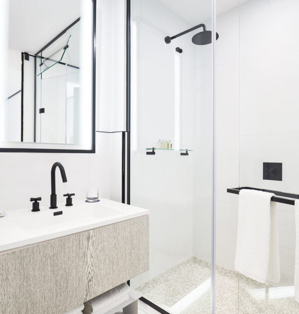 Modern bathroom with glass shower, black fixtures, and vanity.