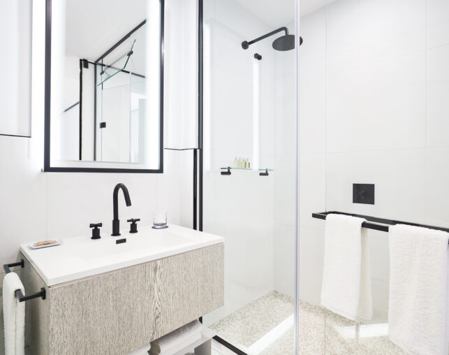 Modern bathroom with glass shower, black fixtures, and vanity.