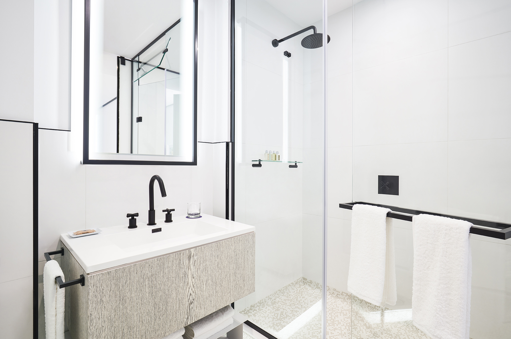 Modern bathroom with glass shower, black fixtures, and vanity.