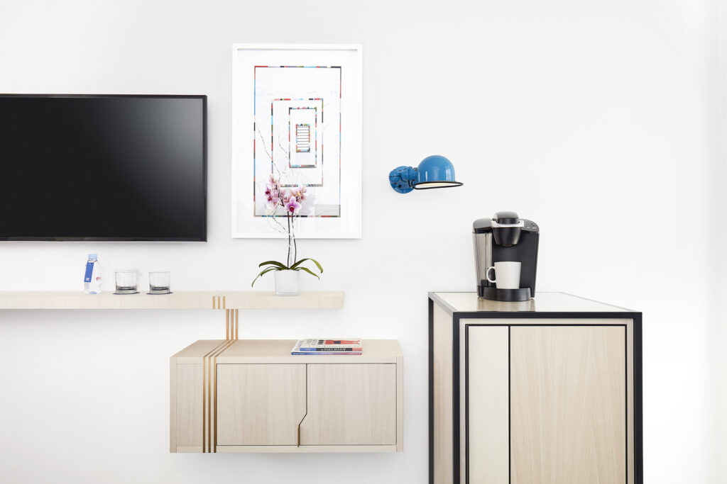 Wall-mounted TV and coffee station with orchid and artwork.