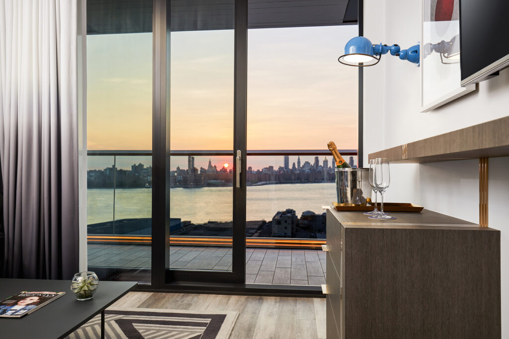 Hotel room with balcony and Manhattan sunset view.