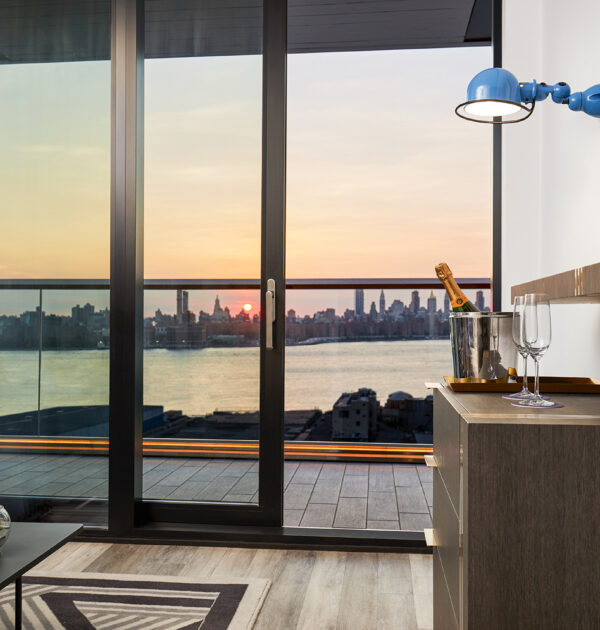 Hotel room with balcony and Manhattan sunset view.