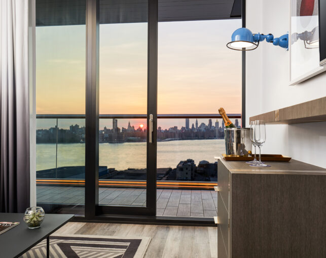Hotel room with balcony and Manhattan sunset view.