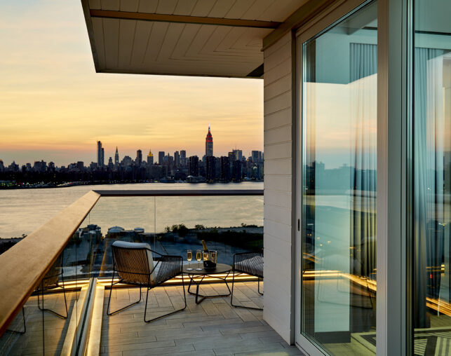 Sunset balcony view with chairs and champagne setup.