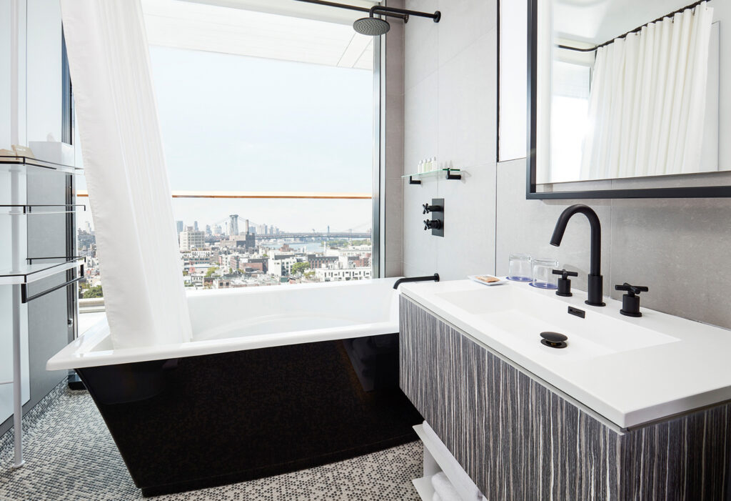 Modern bathroom with tub and city skyline view.