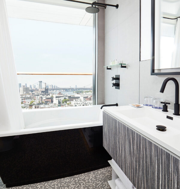 Modern bathroom with tub and city skyline view.