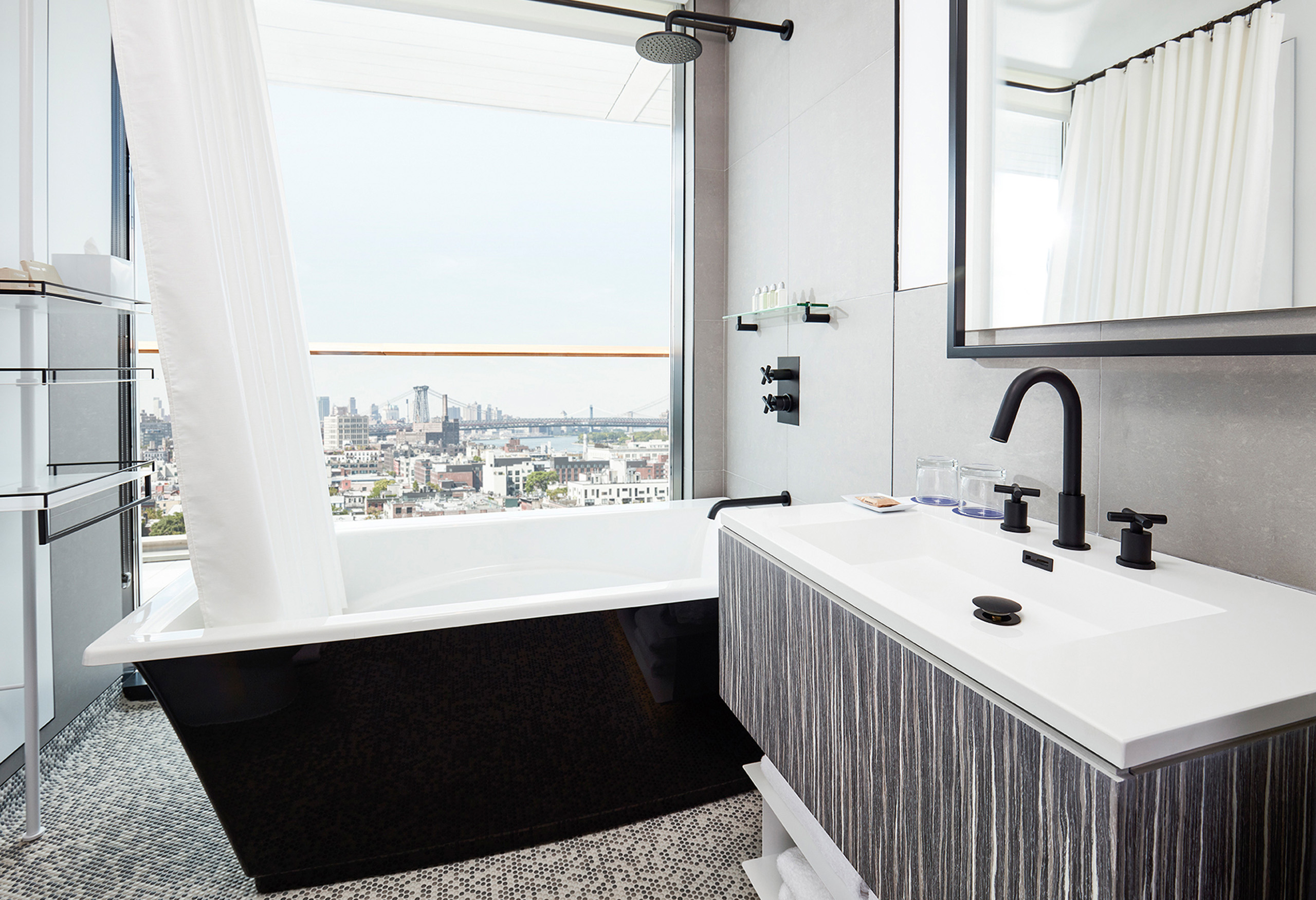 Modern bathroom with tub and city skyline view.