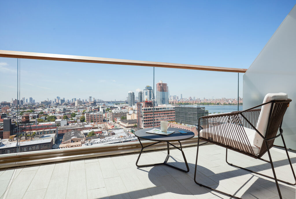 Balcony with city view, chair, and coffee table.