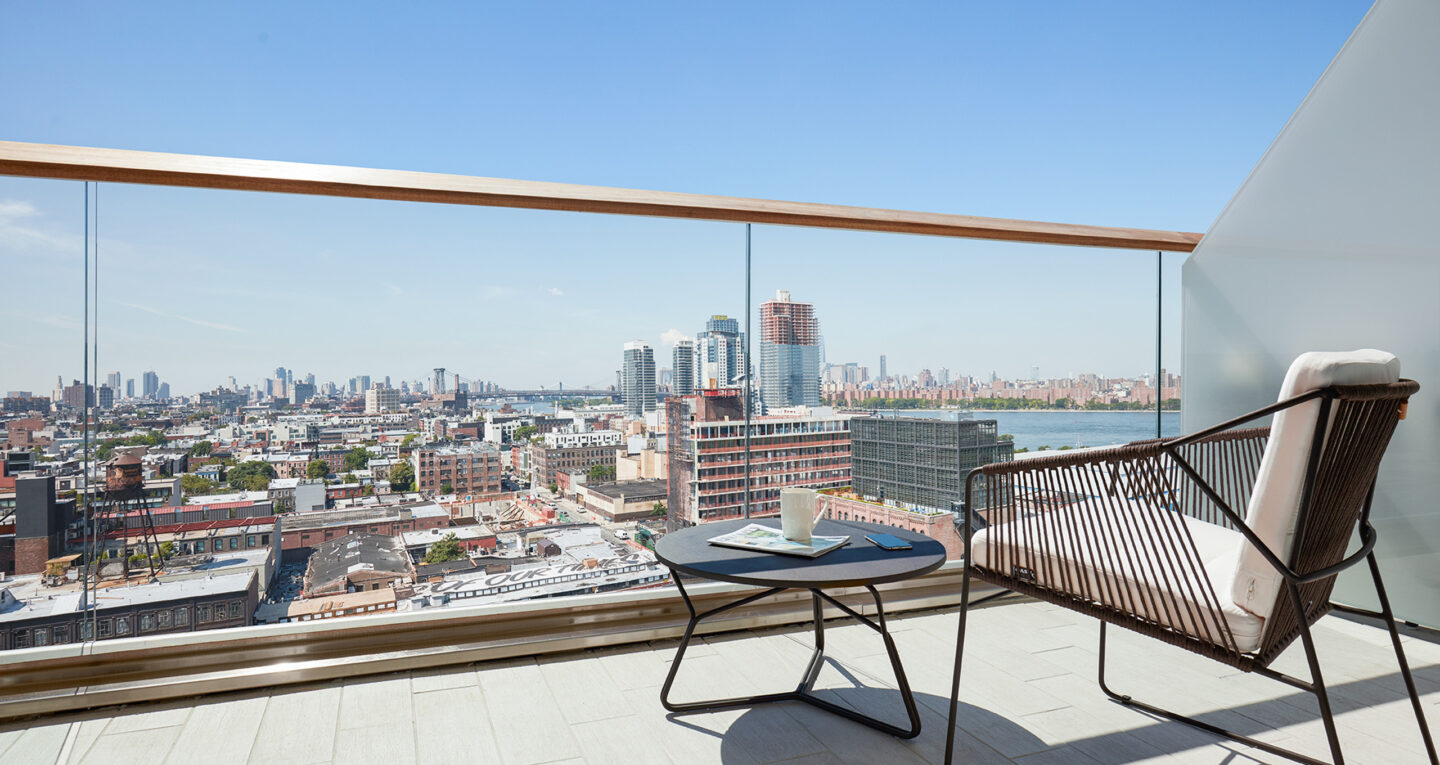 Balcony with city view, chair, and coffee table.