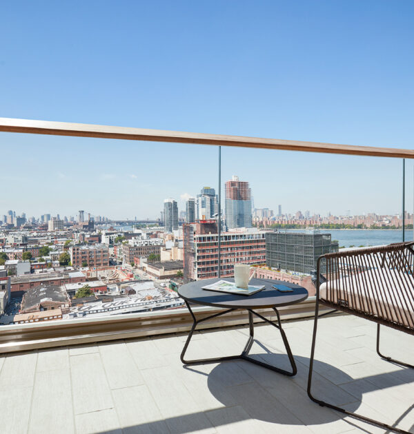 Balcony with city view, chair, and coffee table.