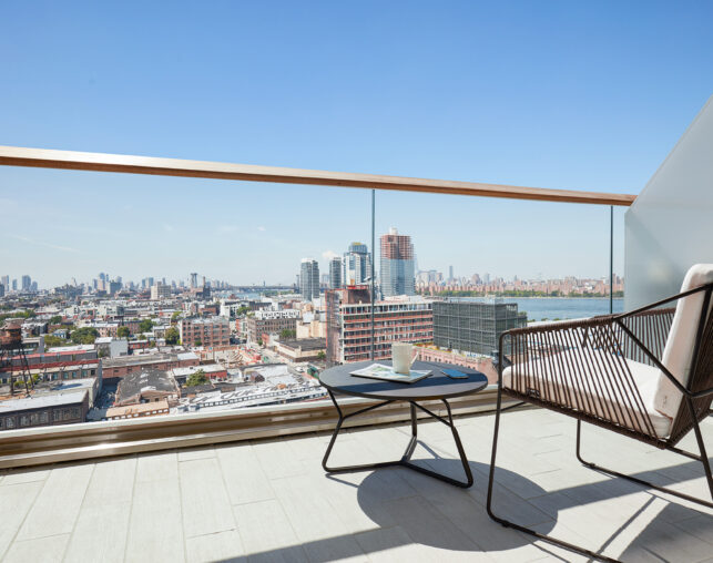 Balcony with city view, chair, and coffee table.