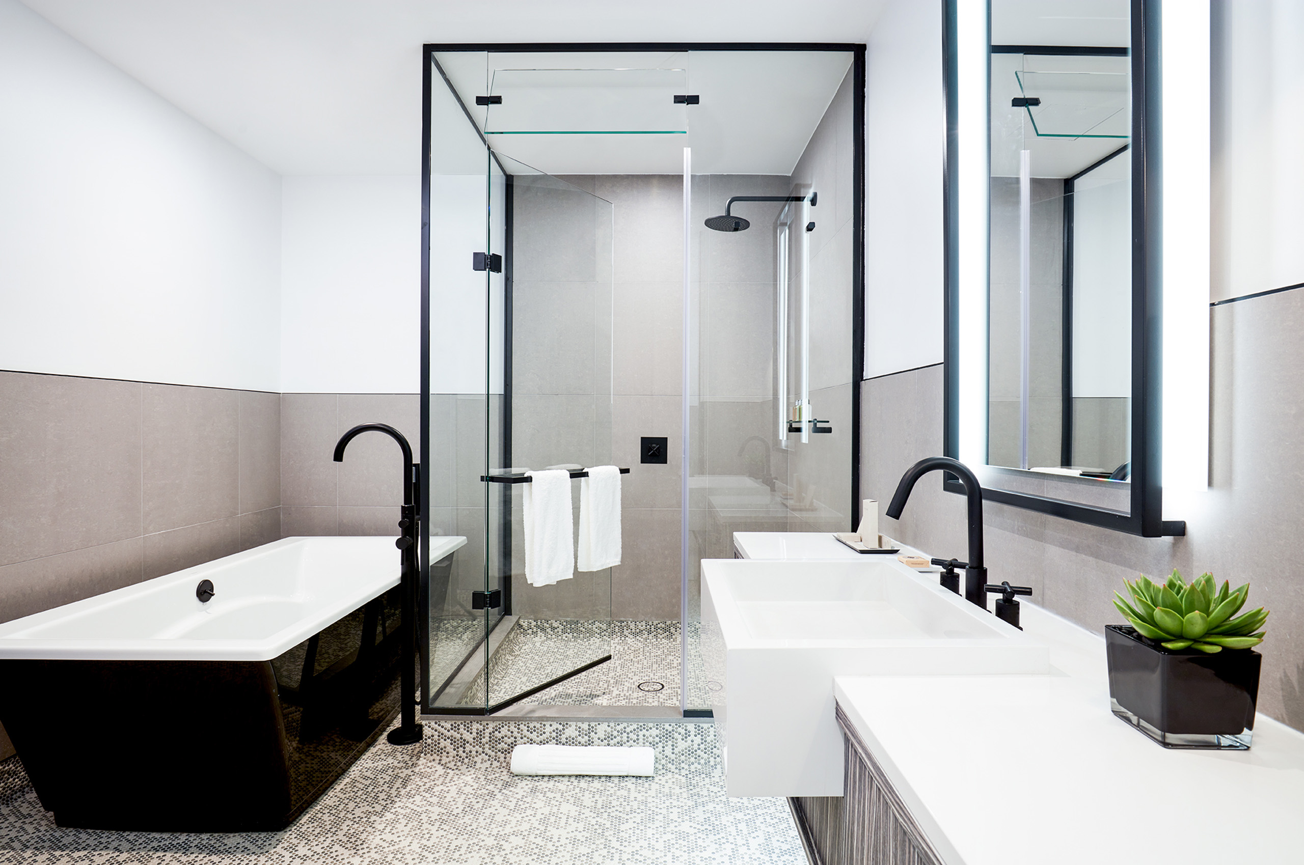 Modern bathroom with tub, shower, and dual sinks.