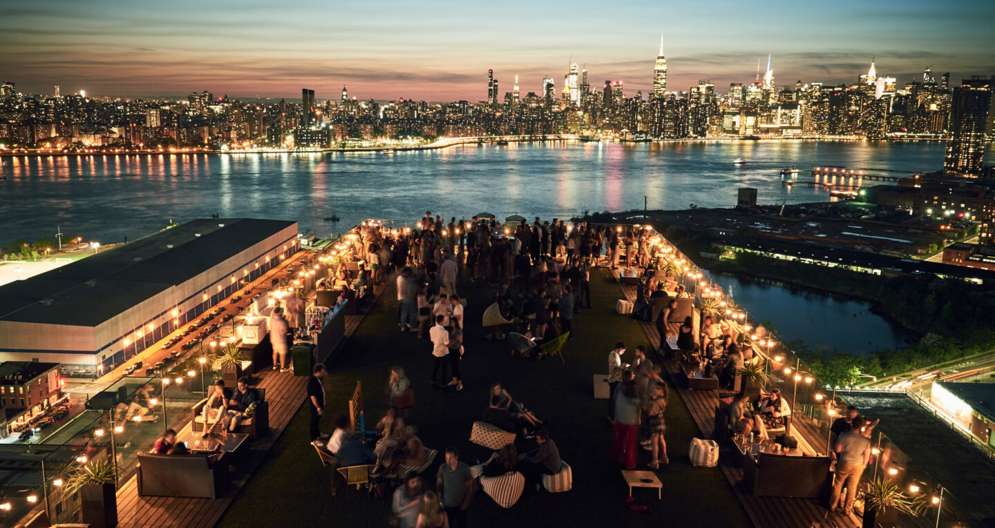 Rooftop party overlooking Manhattan skyline at sunset. Ask ChatGPT