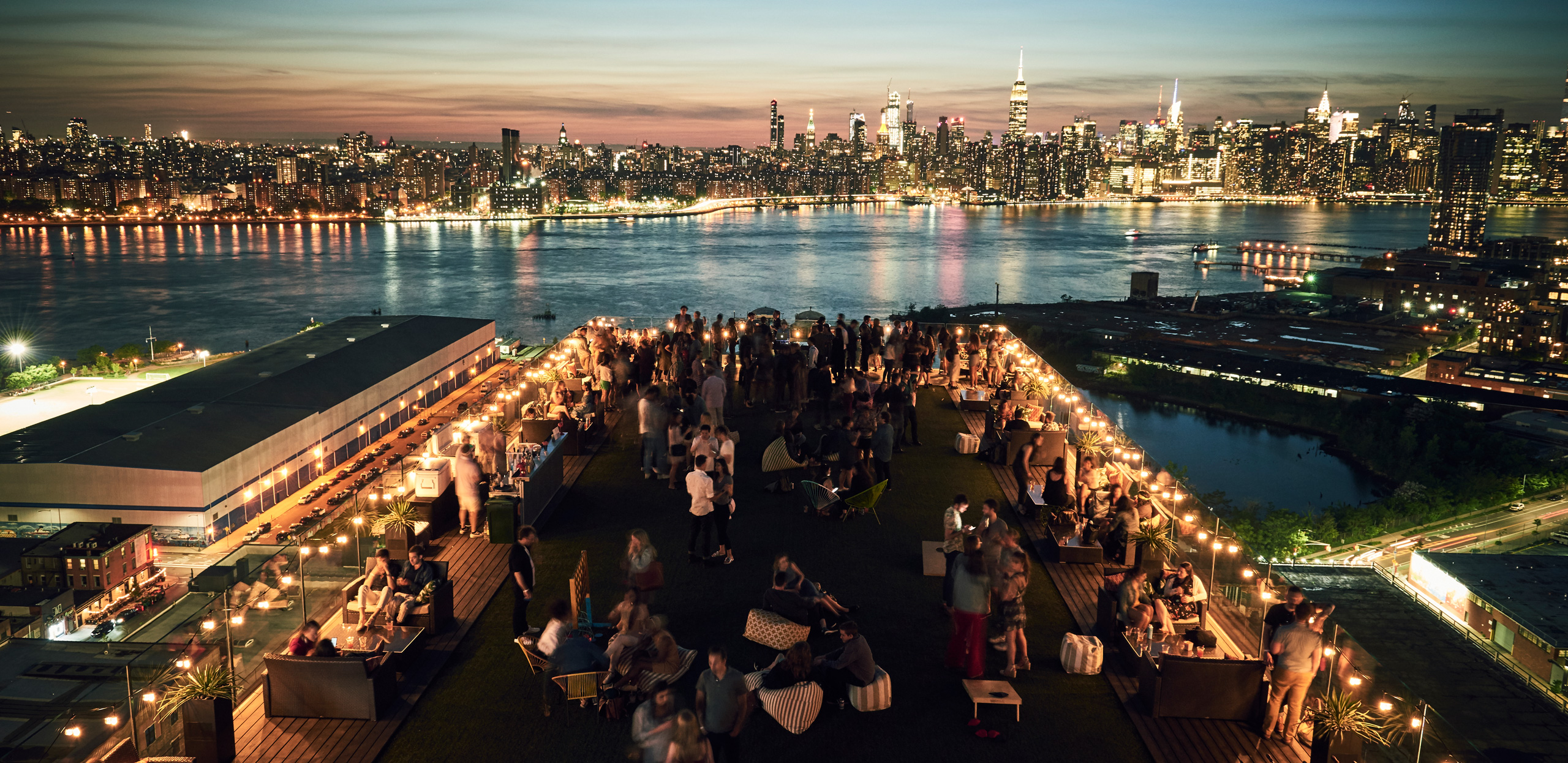 Rooftop party overlooking Manhattan skyline at sunset. Ask ChatGPT