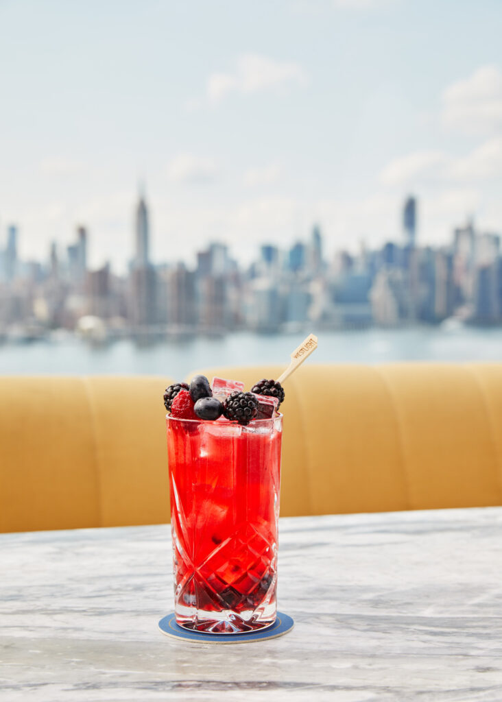Red cocktail topped with fresh berries.