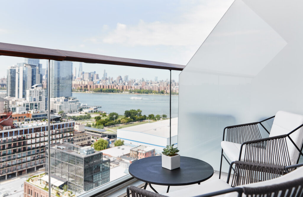 Balcony seating with city and river views, small plant centerpiece