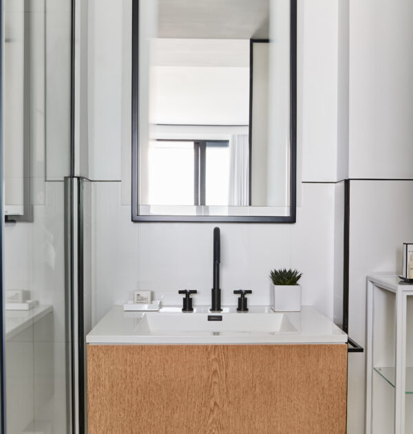 Contemporary bathroom vanity with black fixtures and shower reflection.