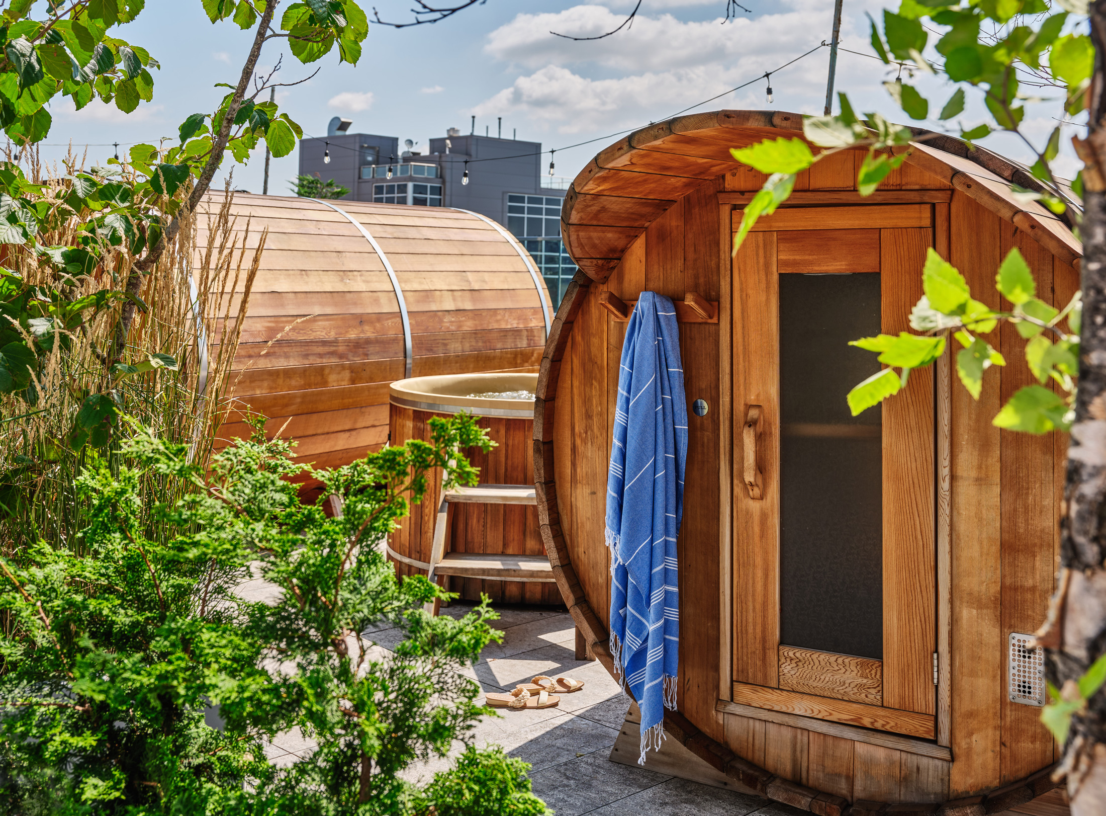 Wooden barrel sauna and hot tub on rooftop terrace.