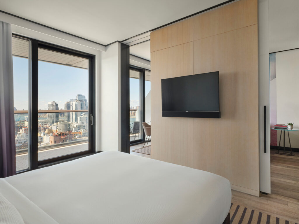 Bedroom with TV and city view balcony.