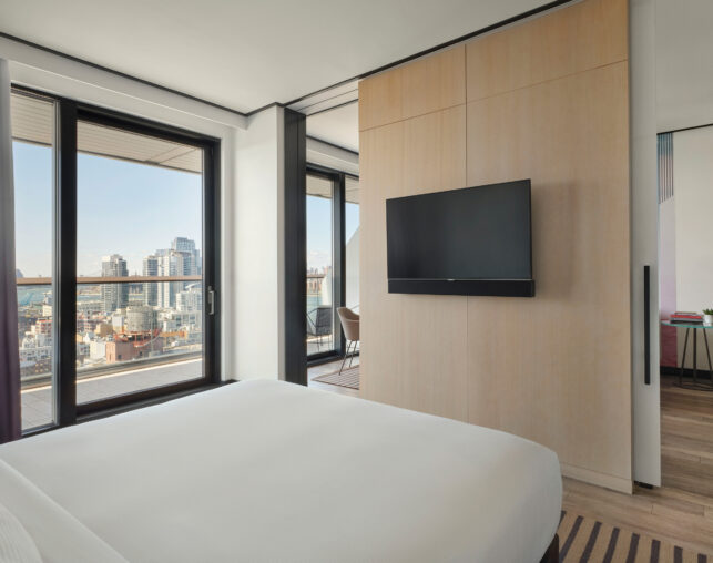 Bedroom with TV and city view balcony.