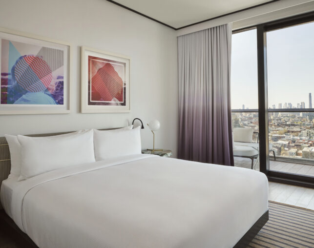 Stylish bedroom with art and skyline view balcony.