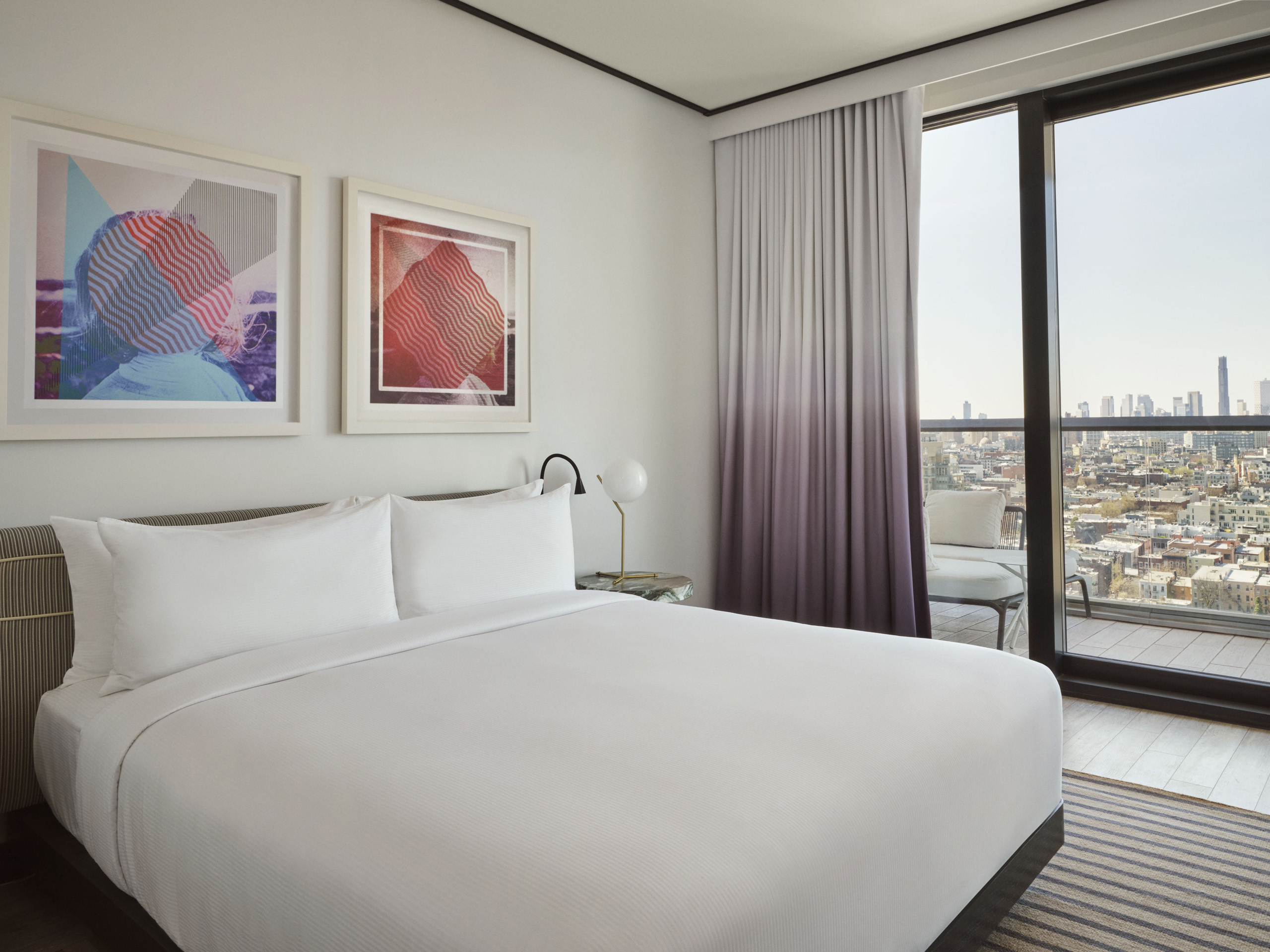 Stylish bedroom with art and skyline view balcony.