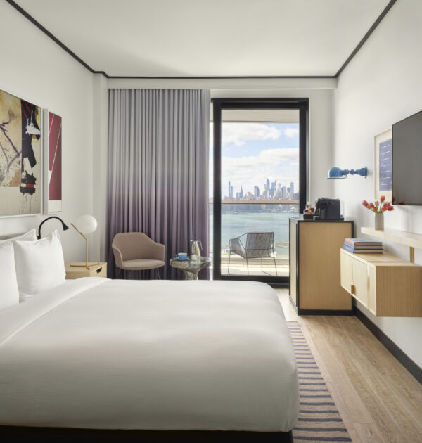 Modern guest room with balcony and city skyline view.