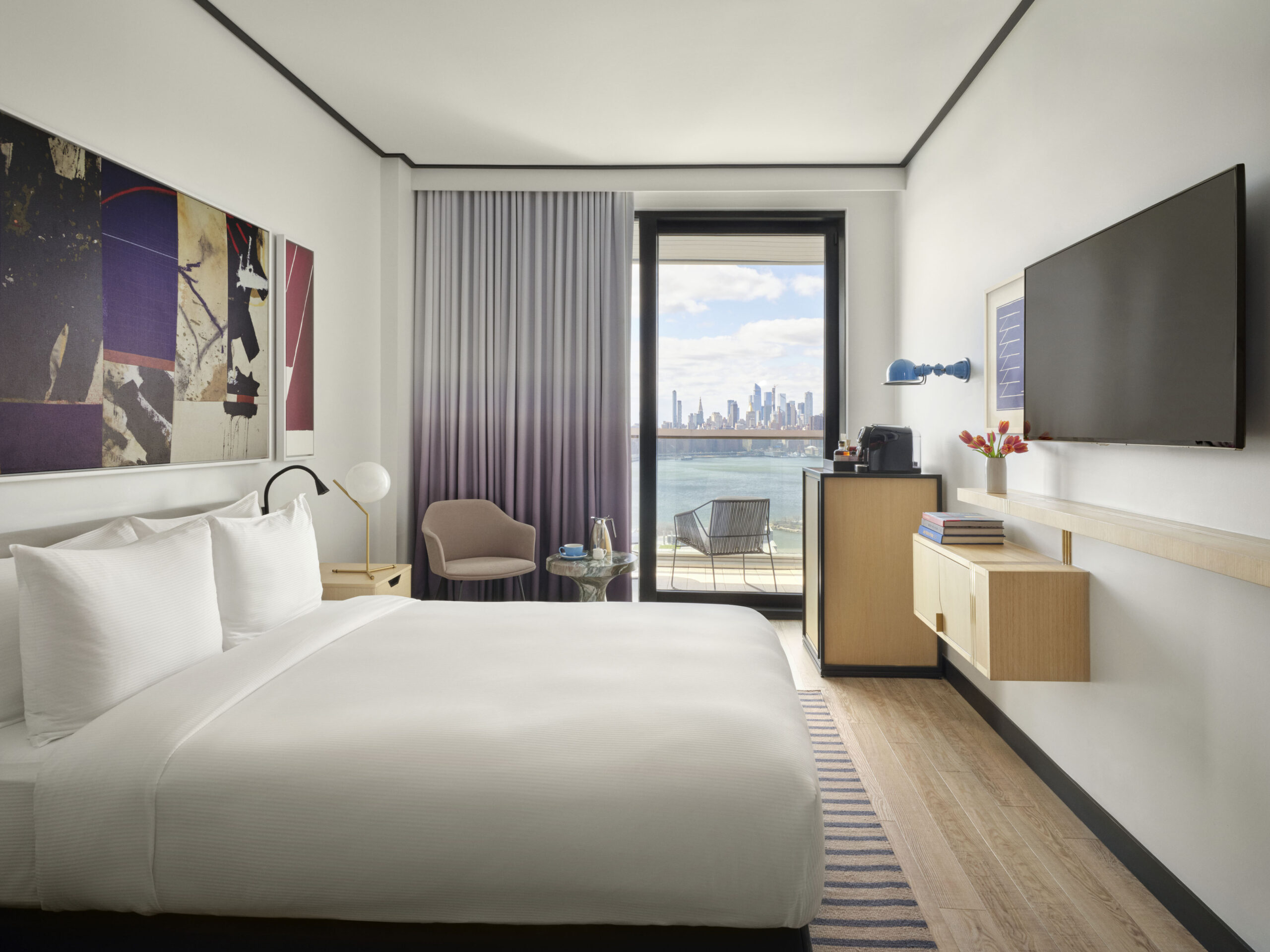 Modern guest room with balcony and city skyline view.