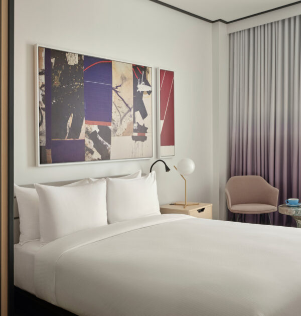 Modern hotel room with bed, abstract art, and balcony