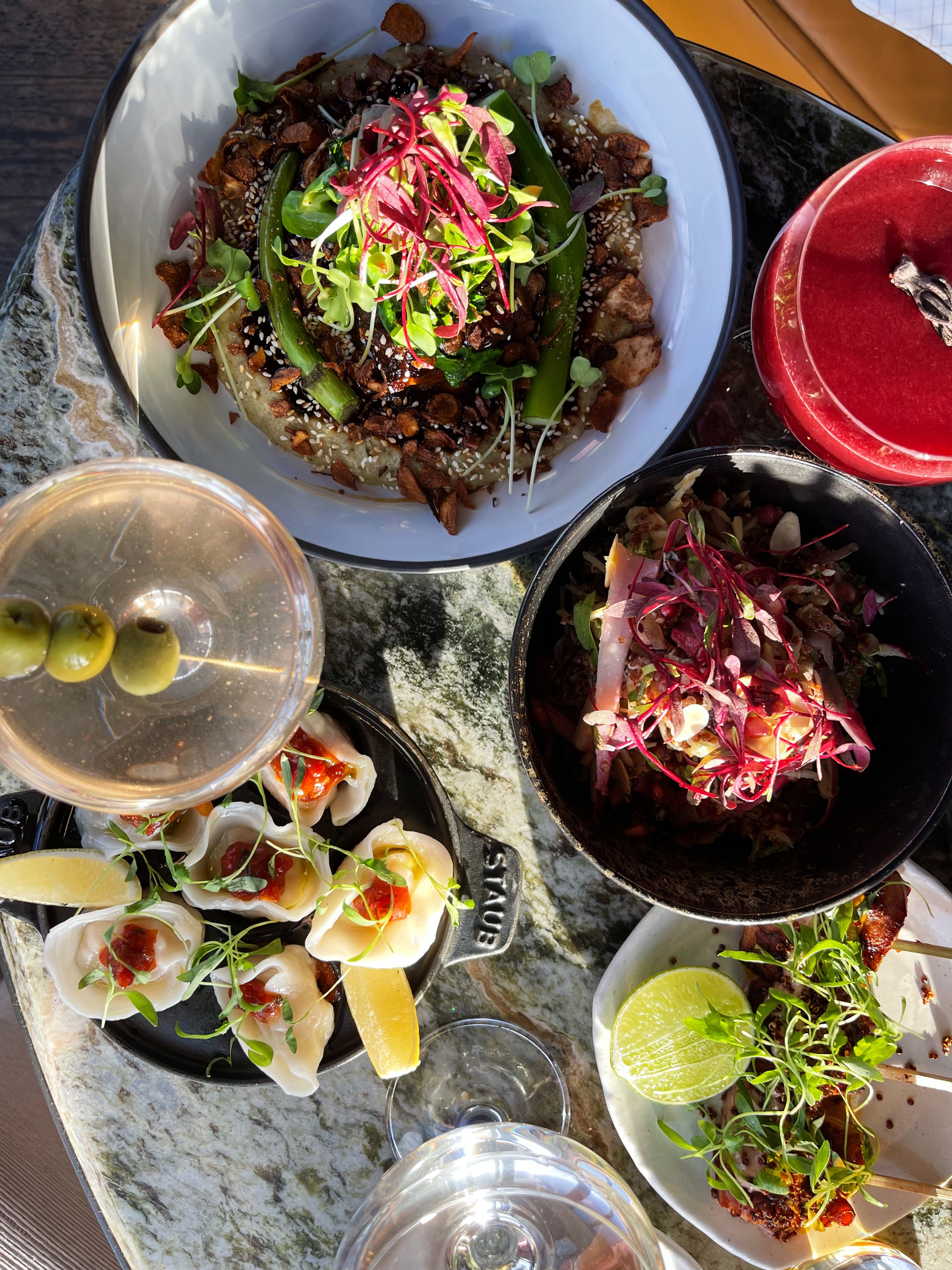 Colorful gourmet dishes and cocktails on a marble table.