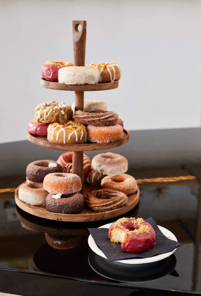 Wooden stand stacked with assorted donuts.
