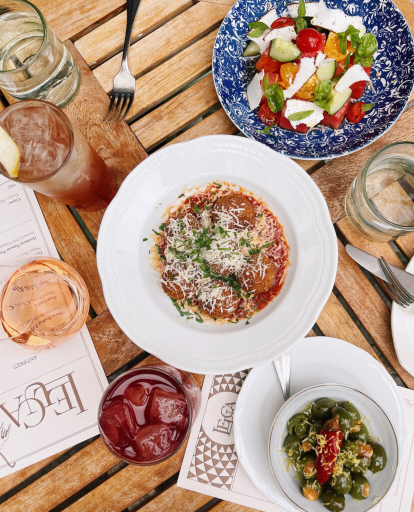 Italian dishes with salad, meatballs, olives, and cocktails.