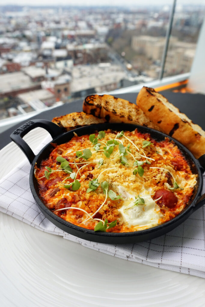 Baked eggs with toasted bread and city view.