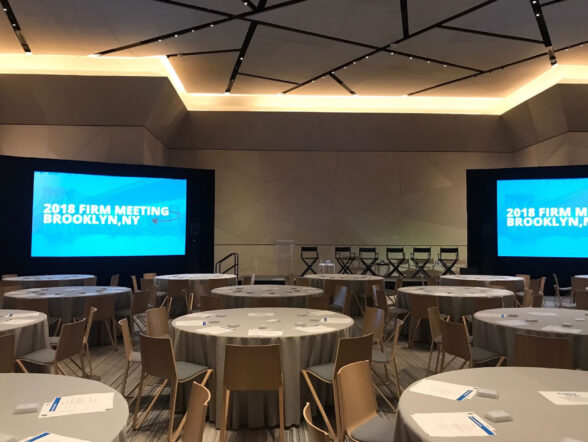 Ballroom arranged for corporate meeting with screens.