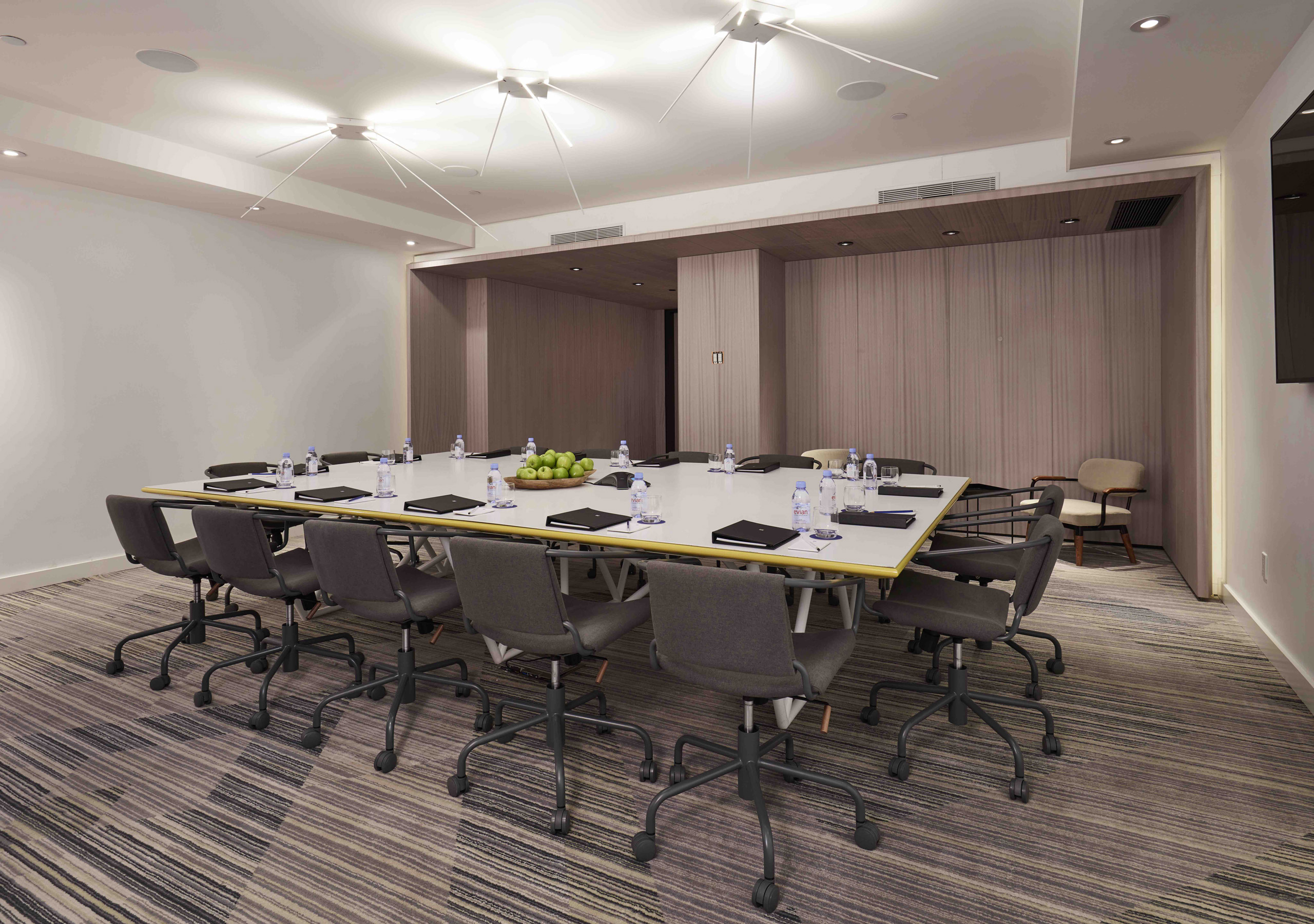 Contemporary boardroom with rolling chairs and square table set for a meeting.