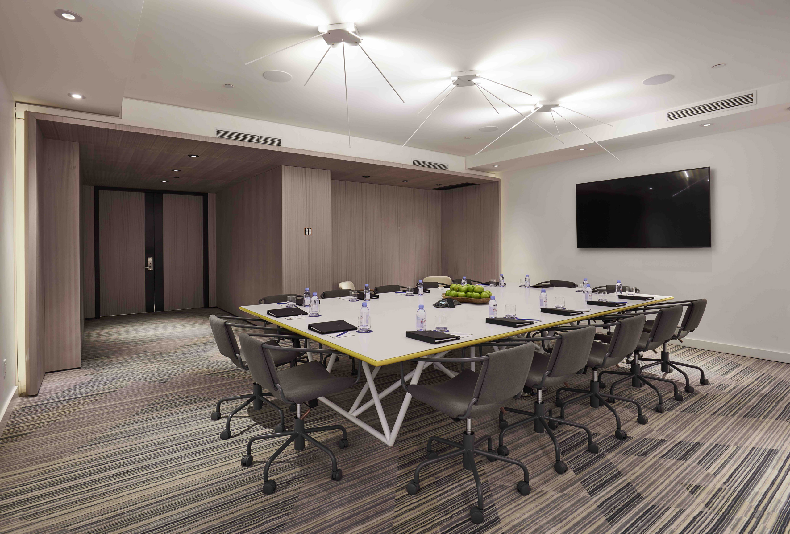 Modern conference setup with central screen, white table, and minimalist lighting.