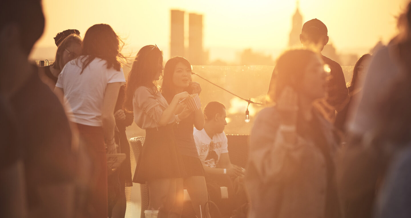 Rooftop crowd at sunset with warm golden light.