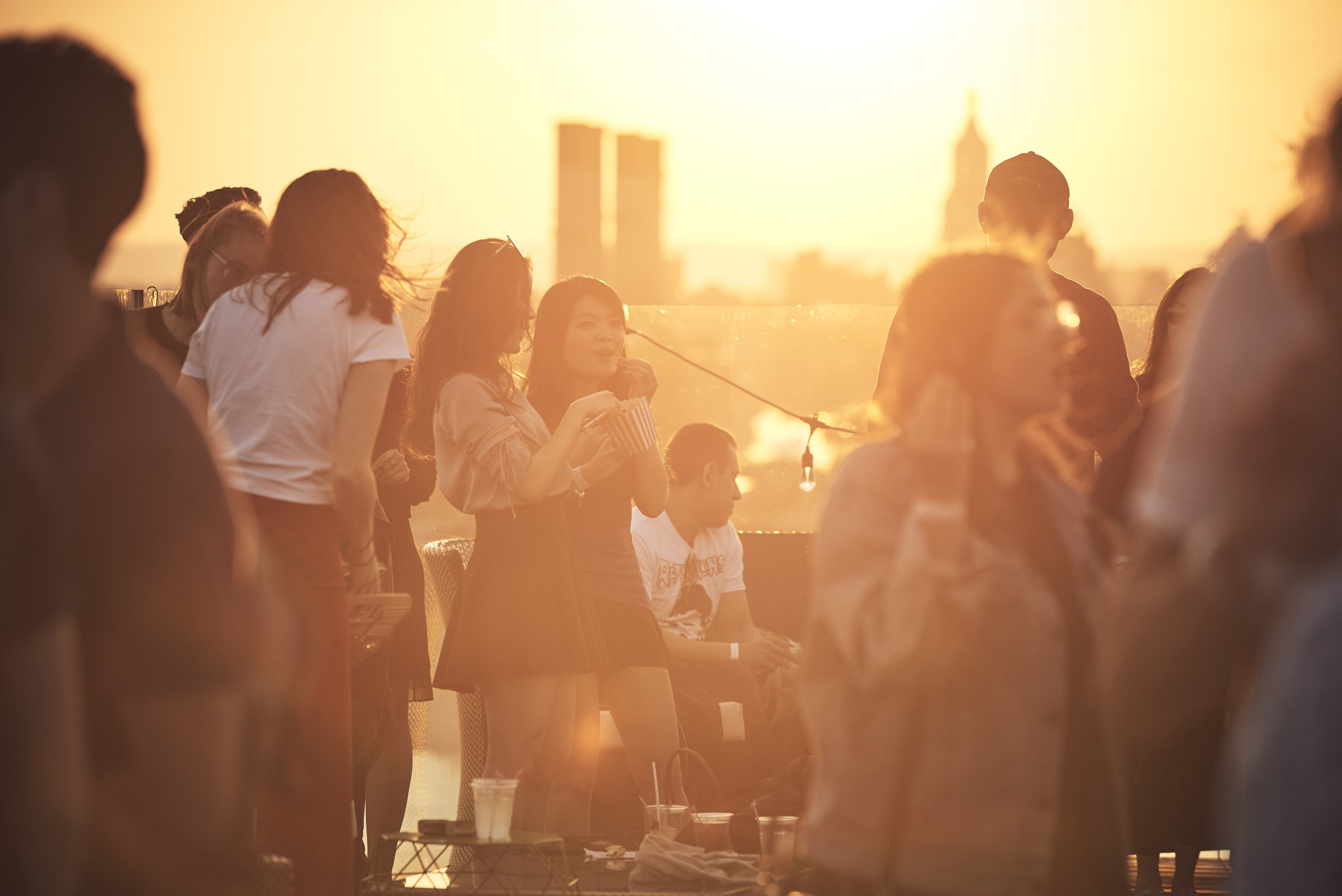 Rooftop crowd at sunset with warm golden light.