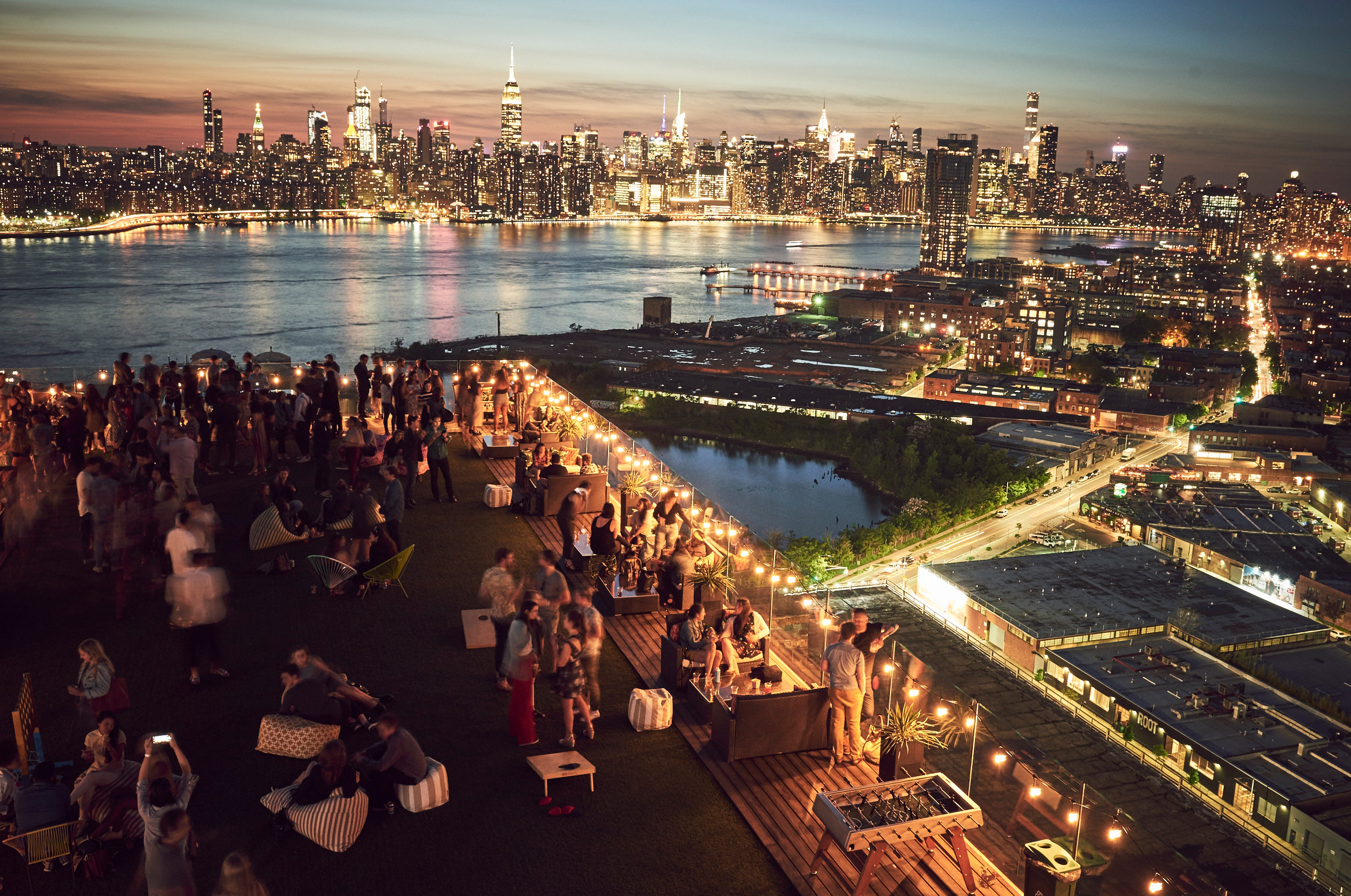 Rooftop party overlooking Manhattan skyline at sunset.