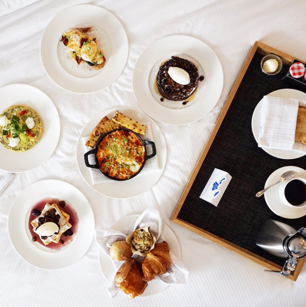 Room service breakfast spread with pastries, pancakes, eggs, and coffee.