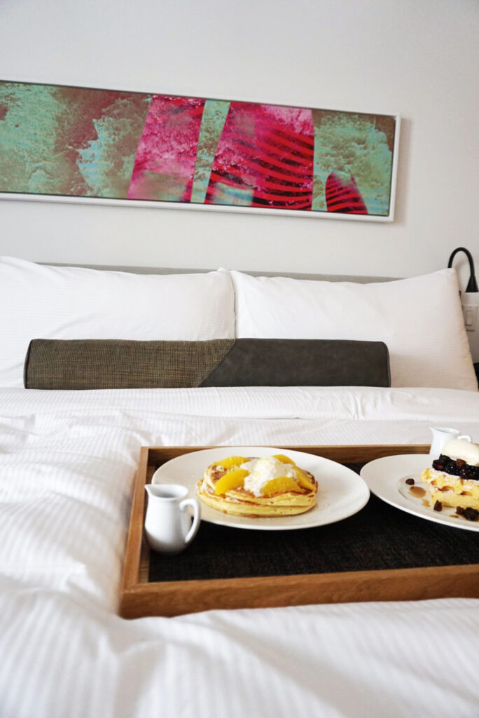 Pancakes and pastries served on bed tray.