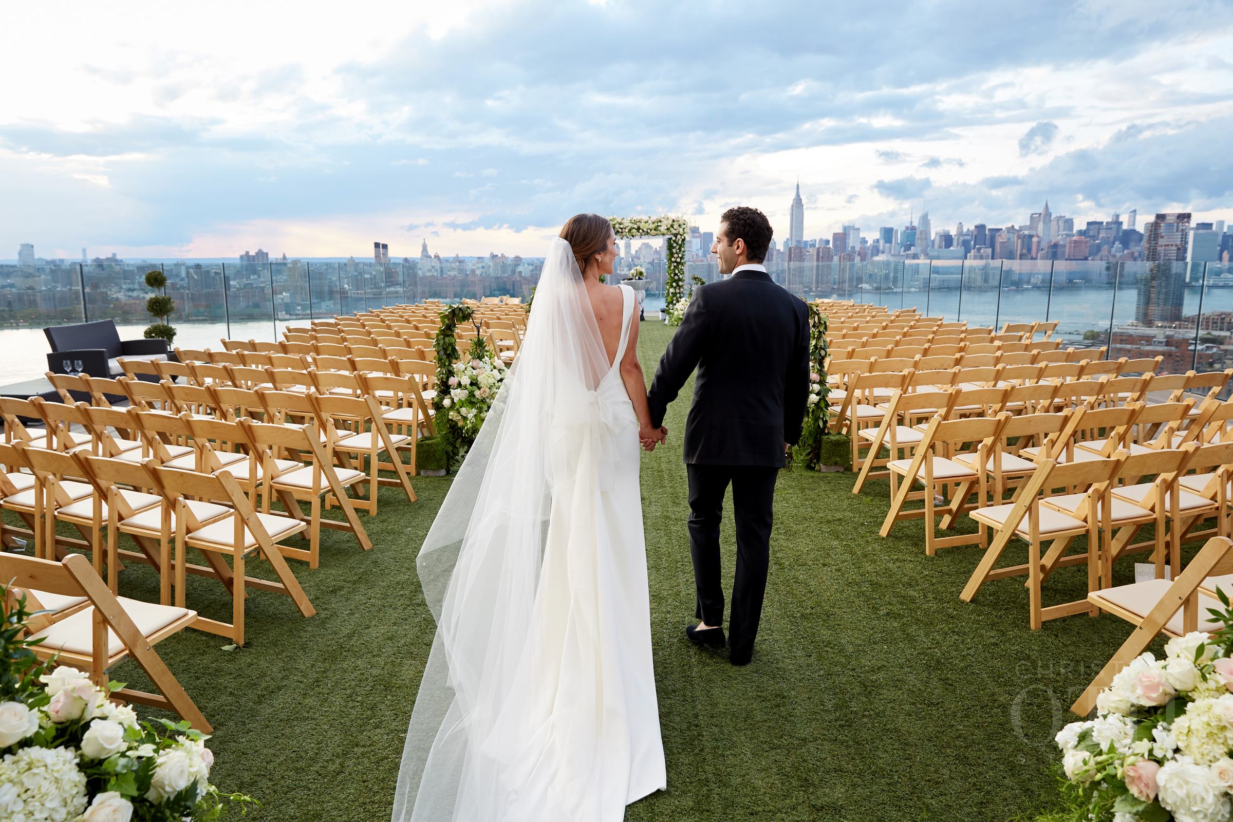 Bride and groom walking down aisle on rooftop wedding terrace.