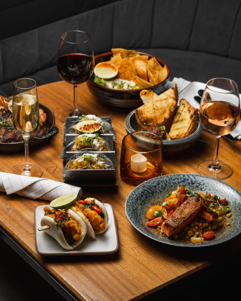 Assorted gourmet dishes and wine on wooden table.