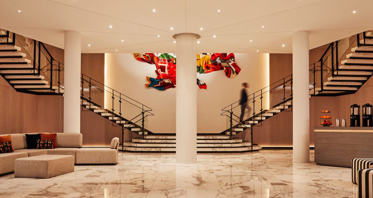 Spacious hotel lobby with marble floors and dual staircases.