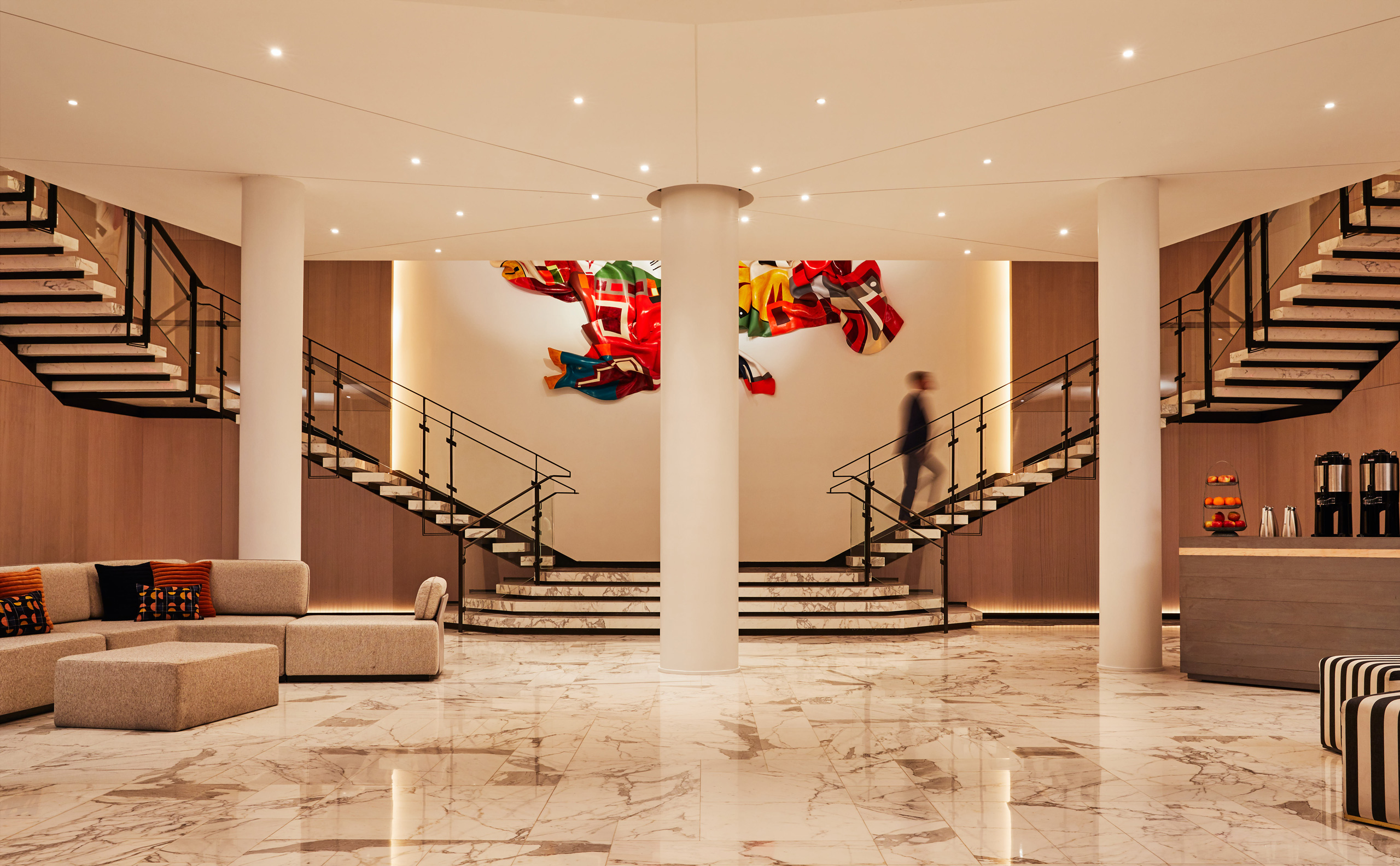 Spacious hotel lobby with marble floors and dual staircases.